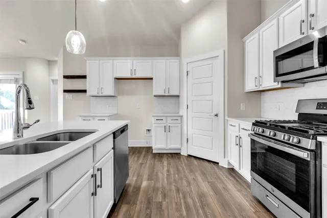 a kitchen with stainless steel appliances granite countertop a sink a stove and a wooden floors