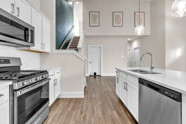 an open kitchen with white cabinets wooden floor and stainless steel appliances