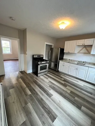 a spacious bedroom with a bed and wooden floor