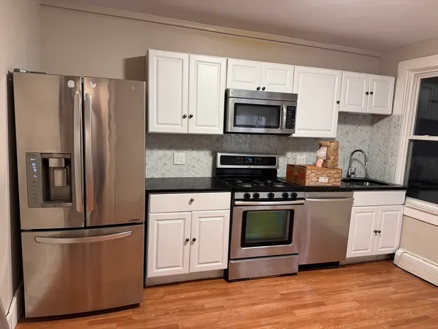 a kitchen with stainless steel appliances granite countertop a refrigerator stove and white cabinets