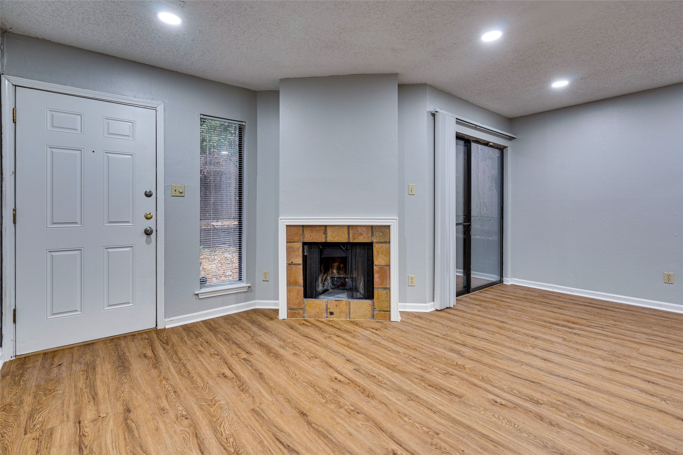 1808 Rio Grande Street, Unit 6 Austin, TX 78701 - Photo 5 of 29 Unfurnished living room with a textured ceiling, recessed lighting, light wood finished floors, and a tiled fireplace