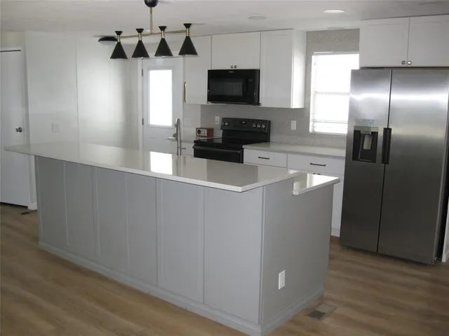 a kitchen with stainless steel appliances a refrigerator a microwave a sink and wooden floor