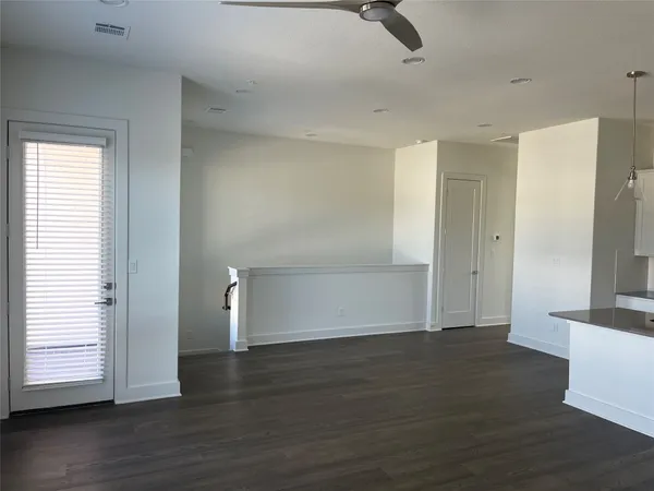 an empty room with wooden floor cabinet and windows