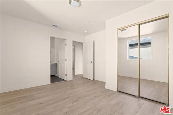 a view of an empty room with wooden floor and closet