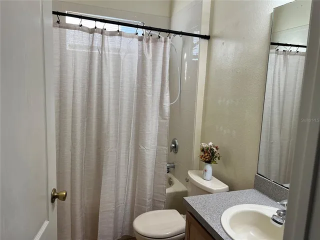 a bathroom with a granite countertop toilet and a shower curtain