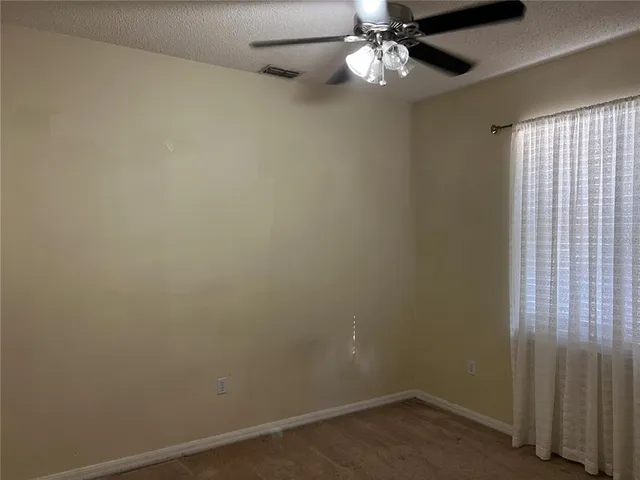 an empty room with a window and a fan