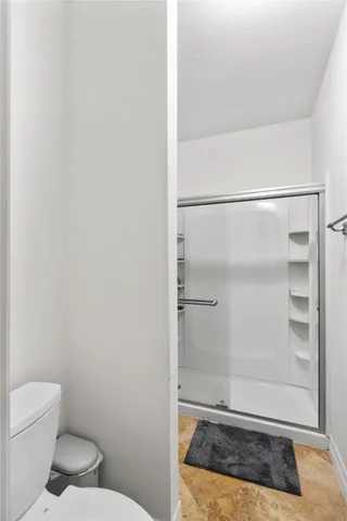 a bathroom with a granite countertop shower and a toilet