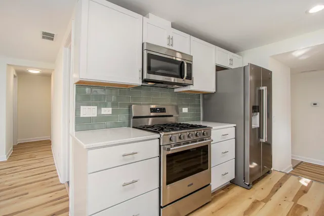 a kitchen with stainless steel appliances white cabinets and a stove top oven