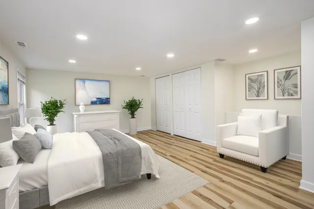 a spacious bedroom with a bed a couch and potted plant on the dresser