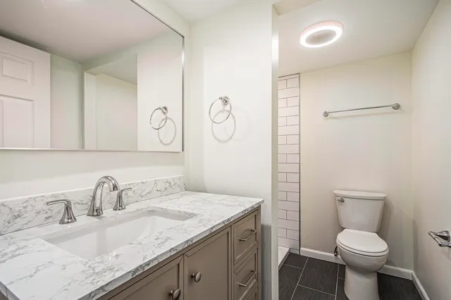 a bathroom with a granite countertop sink toilet and shower