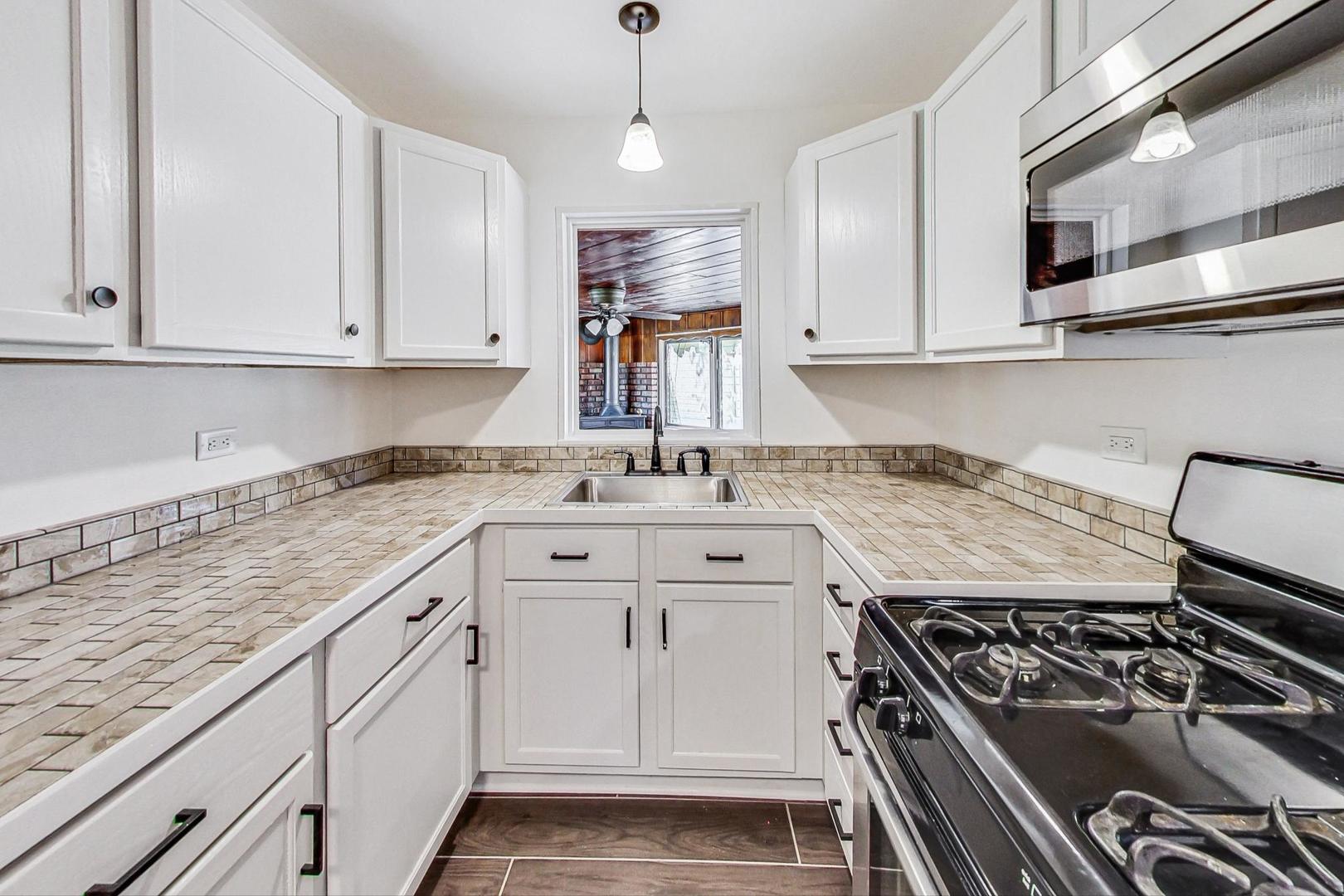 1205 183rd Street Homewood, IL 60430 - Photo 5 of 20 a kitchen with granite countertop a stove and white cabinets