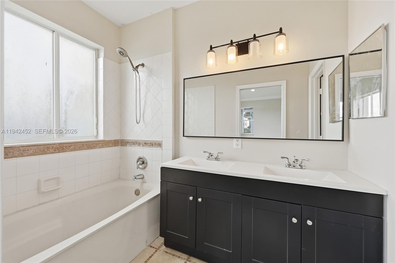 3059 Laurel Ridge Circle Riviera Beach, FL 33404 - Photo 18 of 25 a bathroom with a double vanity sink a mirror a bathtub and shower