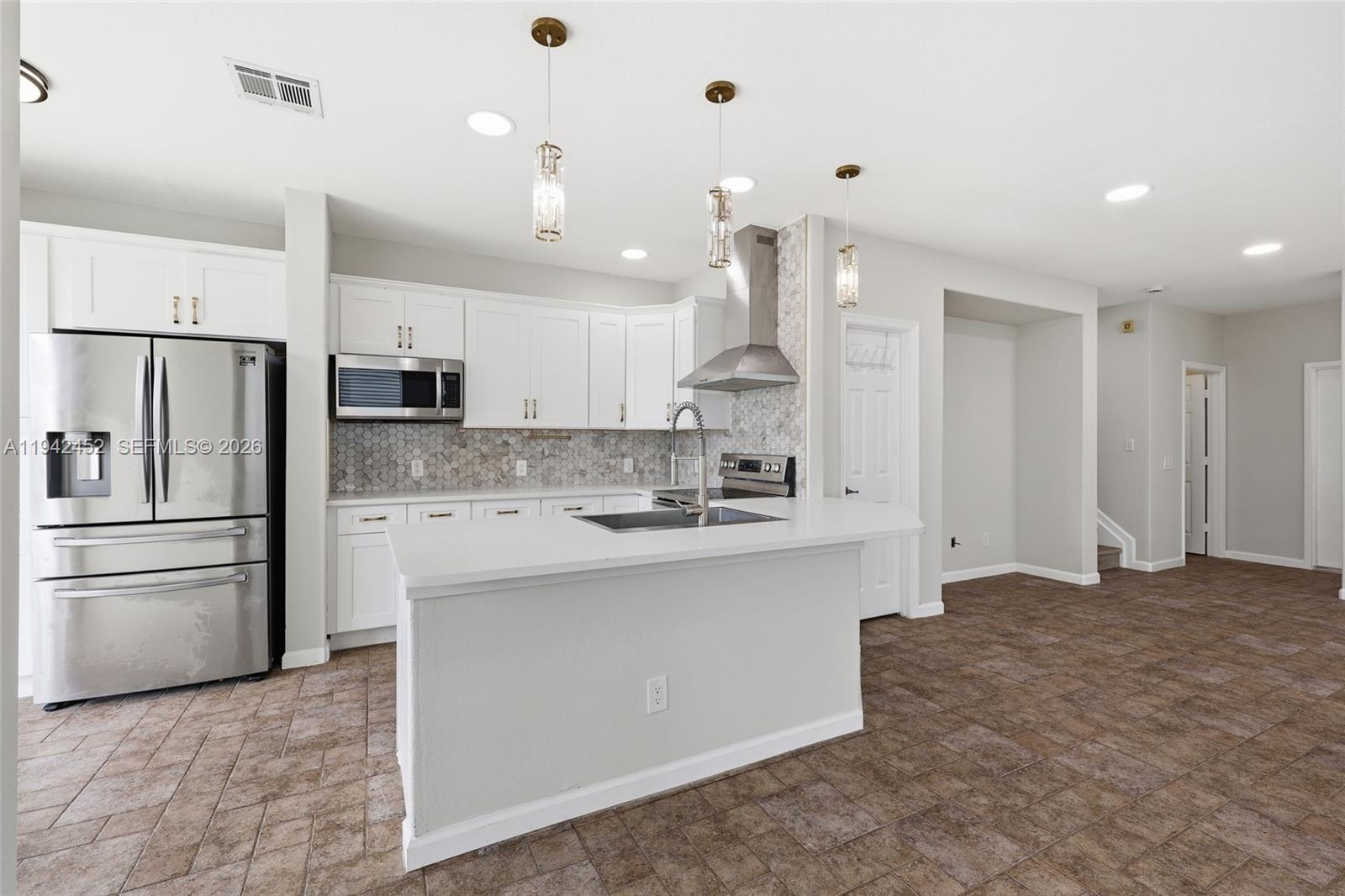 3059 Laurel Ridge Circle Riviera Beach, FL 33404 - Photo 2 of 25 a kitchen with kitchen island a sink stainless steel appliances and cabinets