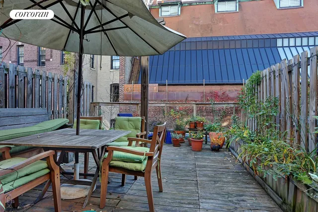 a view of a chairs and table under an umbrella in patio with wooden fence