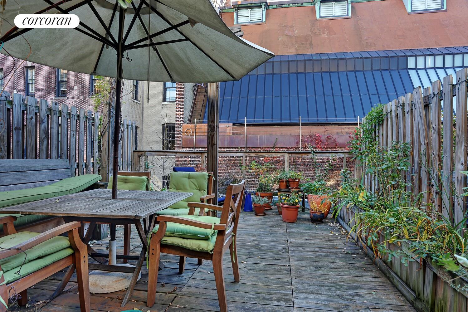 a view of a chairs and table under an umbrella in patio with wooden fence