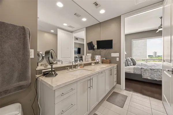 a spacious bathroom with a double vanity sink a mirror and a toilet