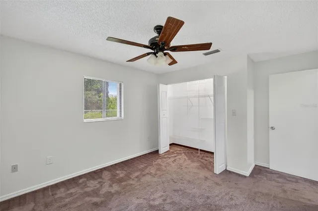 an empty room with a window and a ceiling fan
