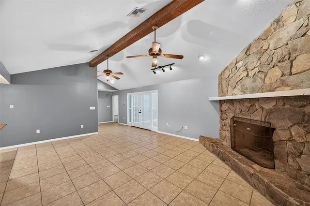 a view of an empty room and chandelier fan