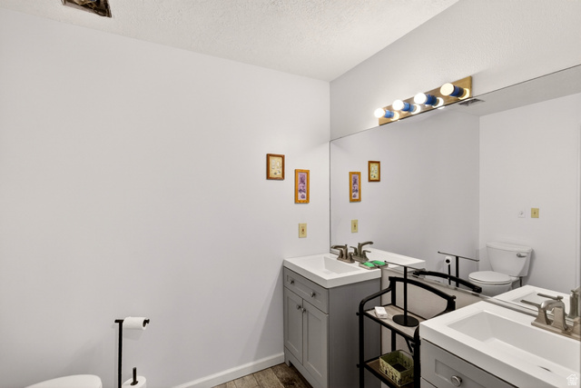 161 West 950 South, Unit Q1 St. George, UT 84770 - Photo 18 of 37 Bathroom featuring two vanities, light wood-type flooring, and a textured ceiling