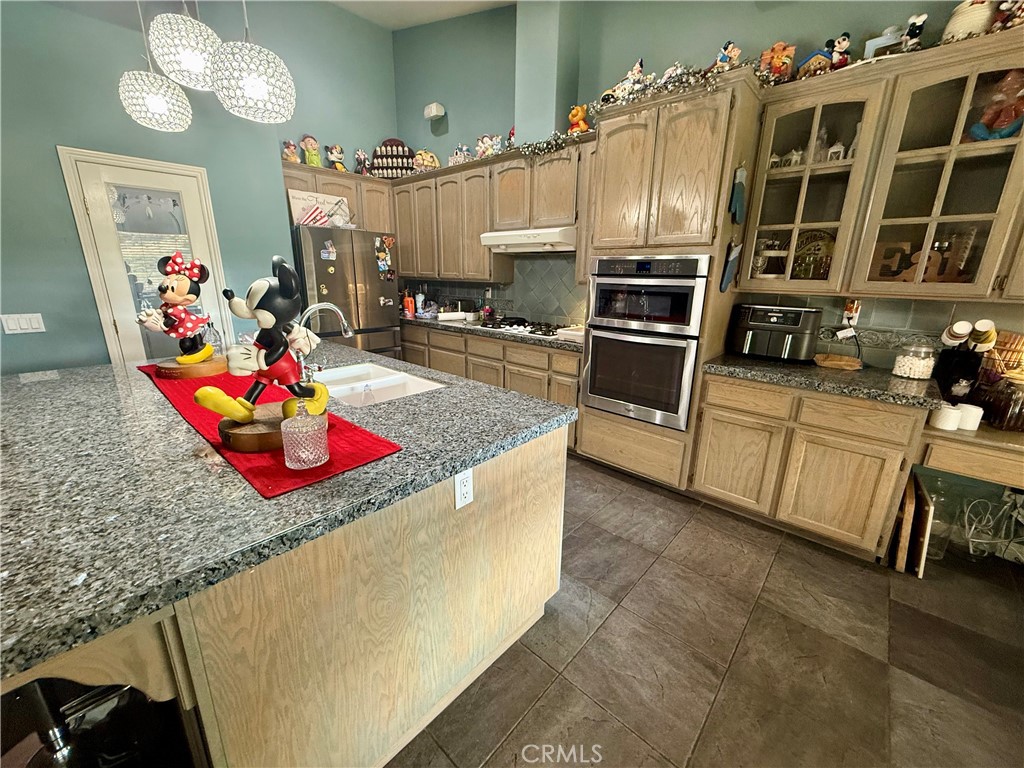 9869 Kehl Canyon Road Cherry Valley, CA 92223 - Photo 9 of 27 a kitchen with stainless steel appliances kitchen island granite countertop a stove and cabinets