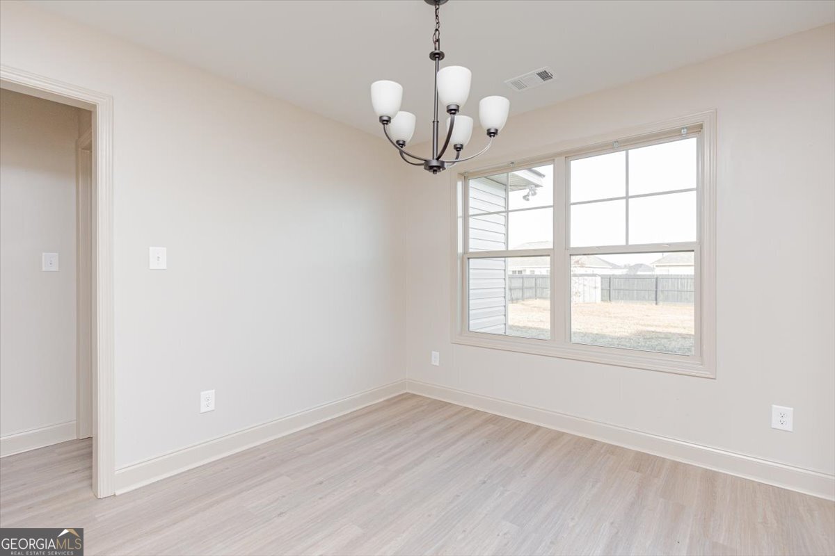 104 Gunner Lane Perry, GA 31069 - Photo 13 of 48 an empty room with wooden floor chandelier and window