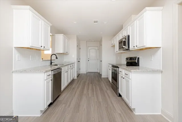 a kitchen with stainless steel appliances granite countertop a stove top oven a sink dishwasher and a refrigerator with wooden floor