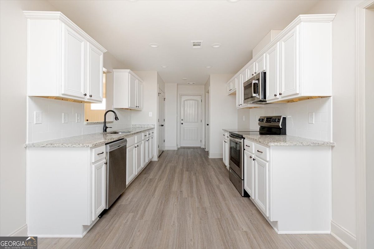 104 Gunner Lane Perry, GA 31069 - Photo 15 of 48 a kitchen with stainless steel appliances granite countertop a stove top oven a sink dishwasher and a refrigerator with wooden floor