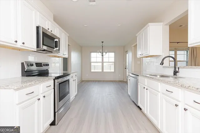 a kitchen with stainless steel appliances granite countertop a stove a sink dishwasher and a microwave oven with white cabinets