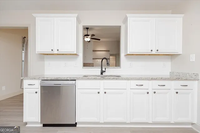a kitchen with granite countertop a sink cabinets and stainless steel appliances