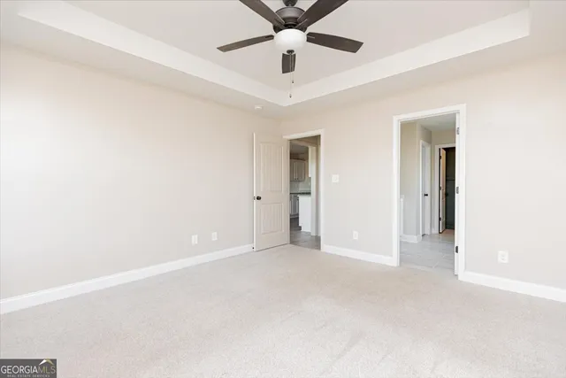 an empty room with chandelier fan and windows