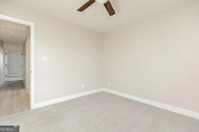 an empty room with a ceiling fan and window