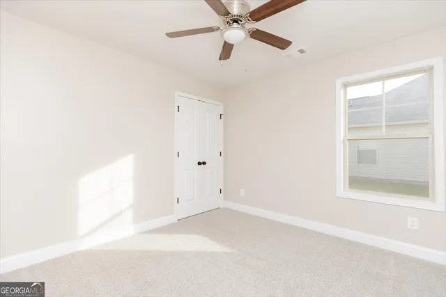 an empty room with a window and a fan