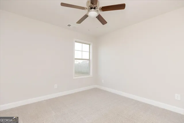 an empty room with chandelier fan and windows
