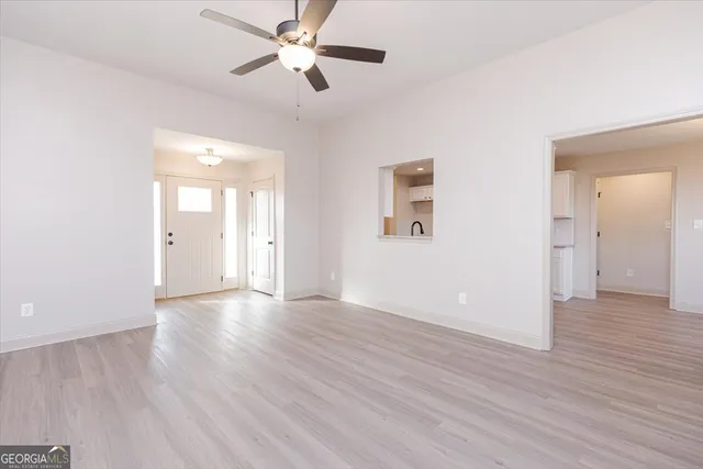 an empty room with wooden floor ceiling fan and windows