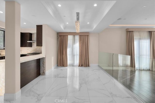 a view of an empty room with kitchen and a window