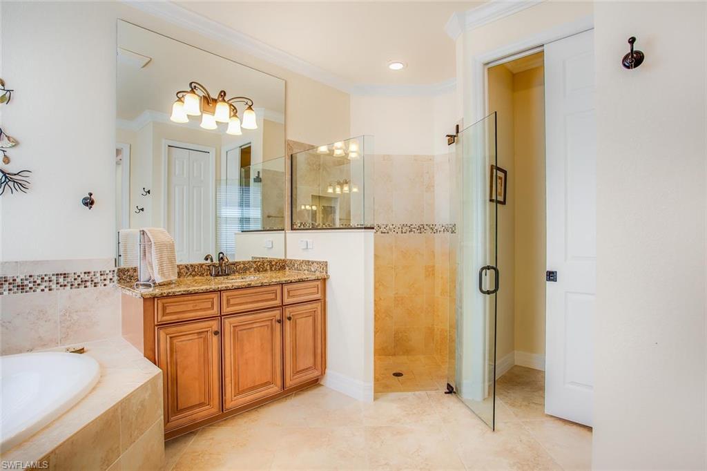 9526 Piacere Way Naples, FL 34113 - Photo 14 of 25 a spacious bathroom with a granite countertop sink a mirror a bathtub and shower
