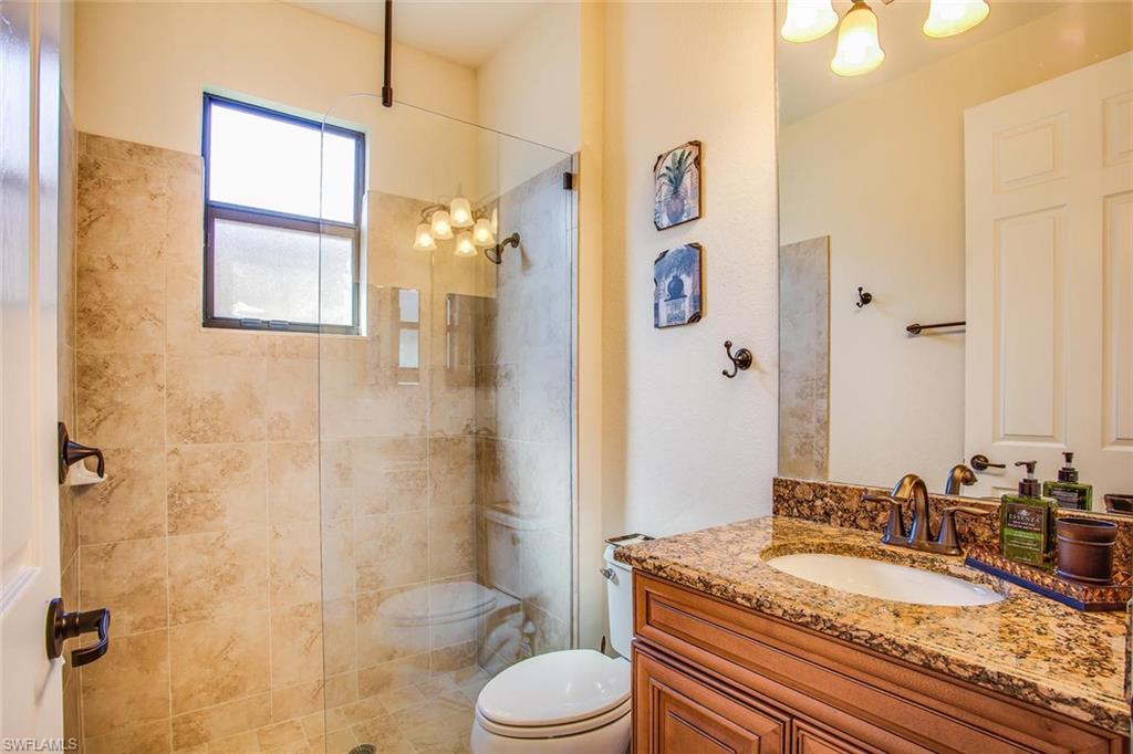 9526 Piacere Way Naples, FL 34113 - Photo 16 of 25 a bathroom with a granite countertop sink toilet a mirror and shower