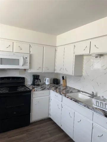 a kitchen with granite countertop white cabinets and white appliances