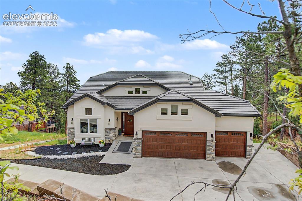 21 Leaming Road Colorado Springs, CO 80906 - Photo 2 of 48 Stucco exterior with stone accents, featuring a multi-gabled tile roof and an integrated two-car garage