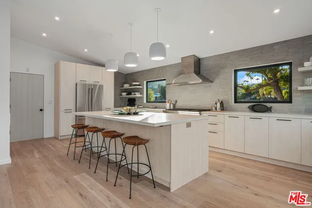 a kitchen with stainless steel appliances granite countertop a sink a stove a refrigerator and island with wooden floor