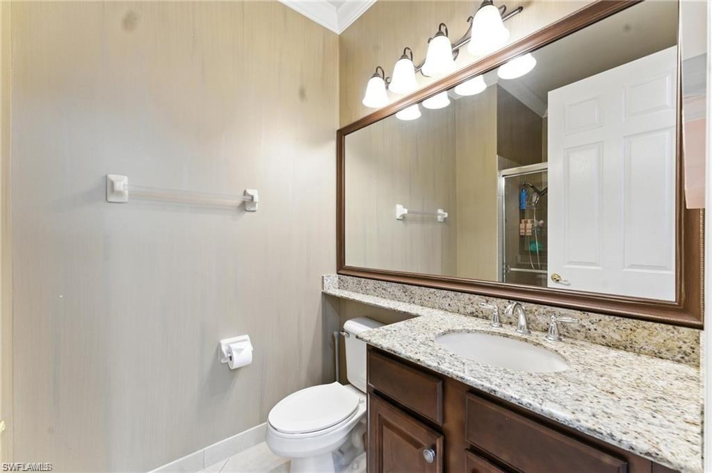 6899 Del Mar Terrace Naples, FL 34105 - Photo 29 of 41 a bathroom with a granite countertop sink a toilet and a mirror