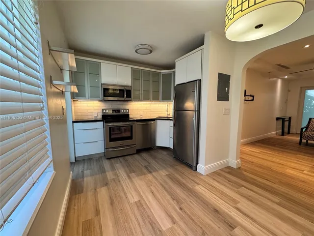 a kitchen with stainless steel appliances granite countertop a refrigerator a stove and a sink with wooden floor