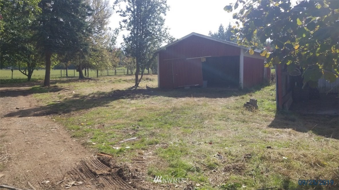 793 Rhoades Road Winlock, WA 98596 - Photo 5 of 24 a backyard of a house with large trees and a covered
