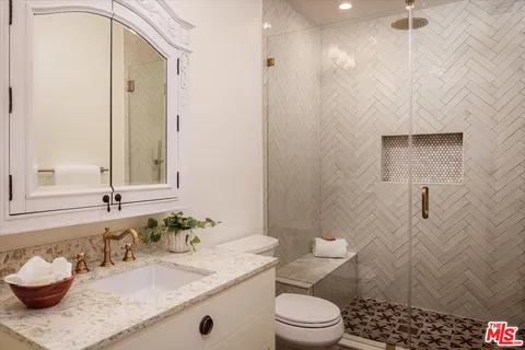 a bathroom with a granite countertop sink a toilet and shower
