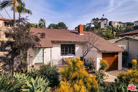 a front view of a house with a yard and potted plants
