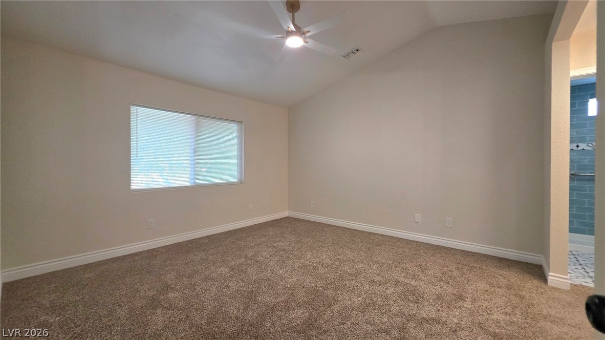 2155 Athol Way Laughlin, NV 89029 - Photo 11 of 19 A tranquil bedroom retreat features vaulted ceilings and plush carpet, with a glimpse into a tiled bathroom.