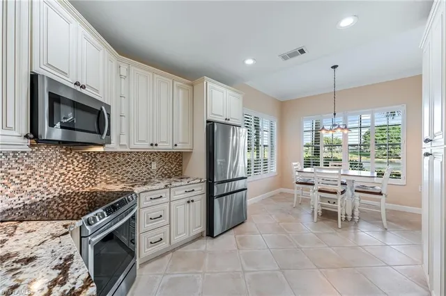 a kitchen with stainless steel appliances granite countertop a stove top oven a refrigerator a sink and a microwave