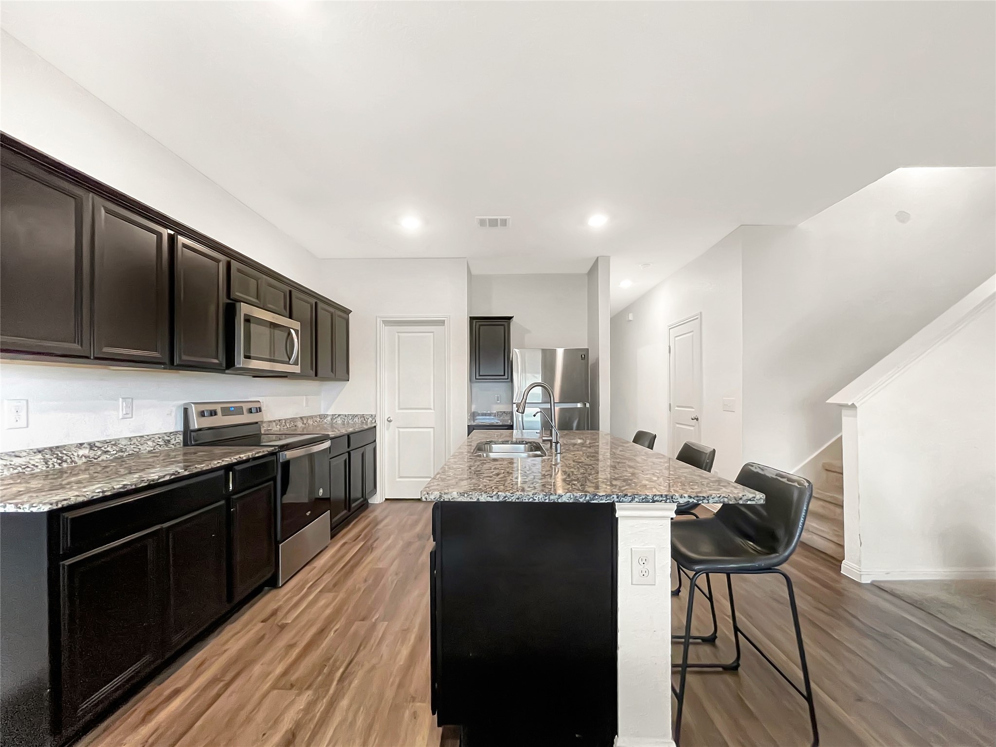 19221 Nathan Scott Way Manor, TX 78653 - Photo 5 of 15 a large kitchen with stainless steel appliances kitchen island granite countertop a sink and cabinets