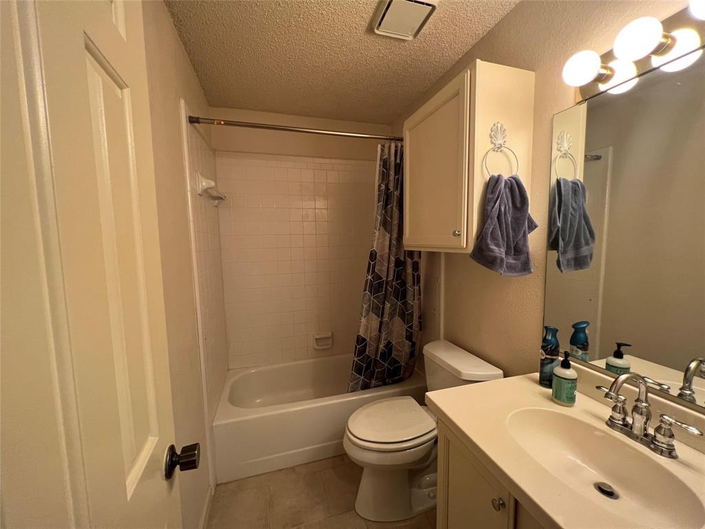 3129 Sappington Place Fort Worth, TX 76116 - Photo 14 of 15 Bathroom featuring a textured ceiling, shower / bathtub combination with curtain, vanity, and light tile patterned floors