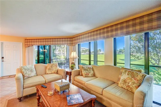 a living room with furniture kitchen view and a large window